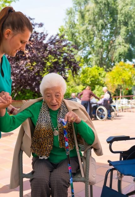 Portrait of an elderly woman with the nurse in the wheelchair in the garden of a nursing